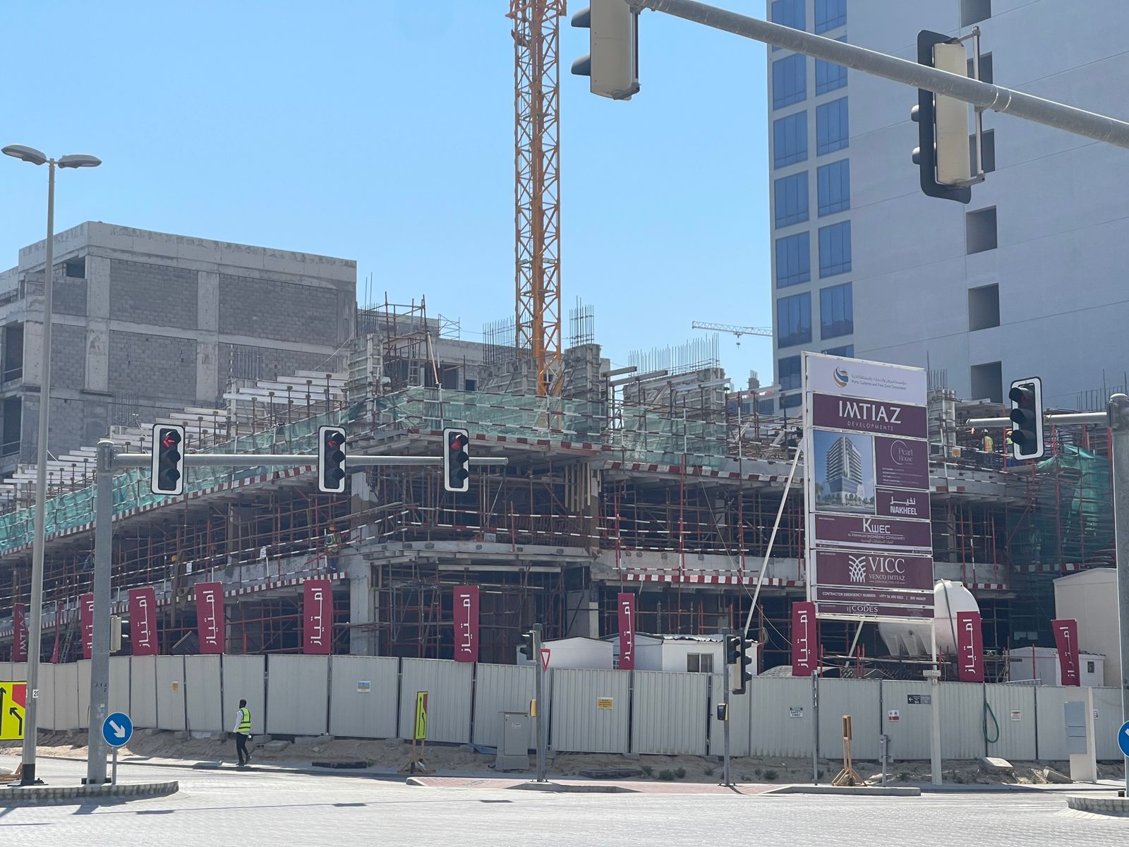 Pearl House By Imtiaz Construction site featuring scaffolding, traffic lights, and a large sign for Imtiaz Developments in a clear blue sky.